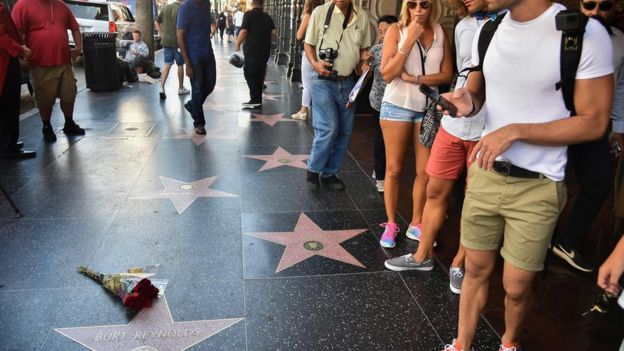 Tourists stand near flowers placed on the star of actor Burt Reynolds on the Hollywood walk of fame in Hollywood