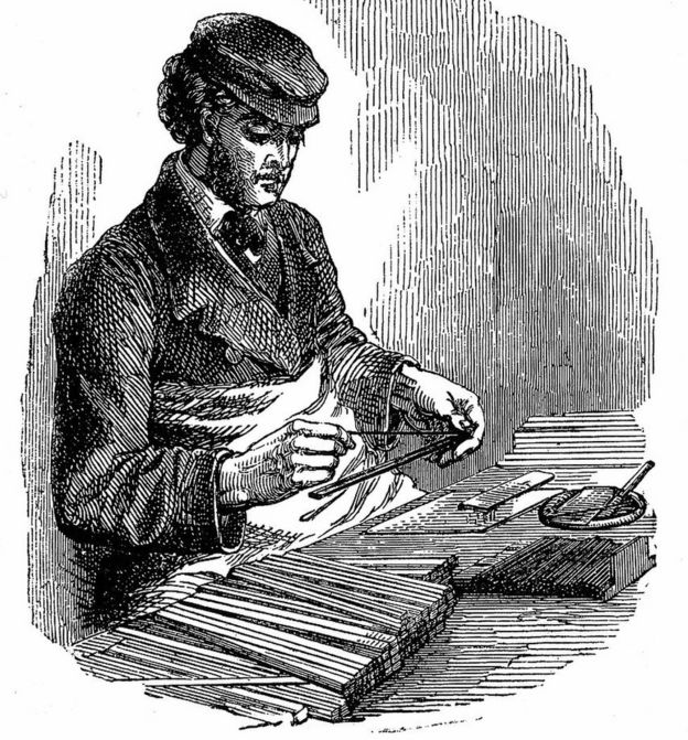 Un hombre inserta grafito entre palos de madera de cedro en un grabado de 1872.