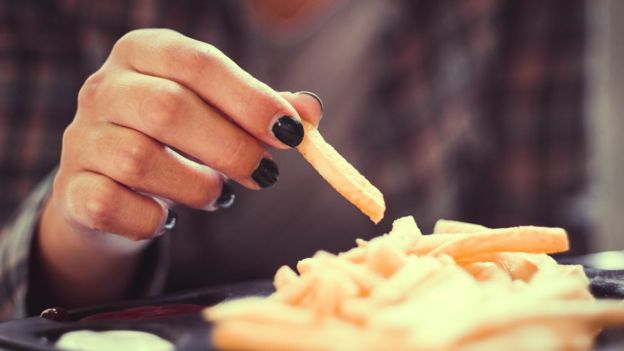 Mãos de mulher comendo batata-frita