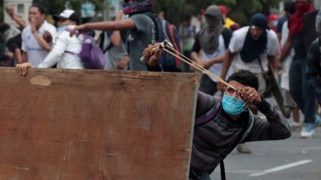 A demonstrator uses a slingshot to hurl stones toward riot police during a protest over the pension plans of the Nicaraguan Social Security Institute (INSS) in Managua, Nicaragua April 20, 2018