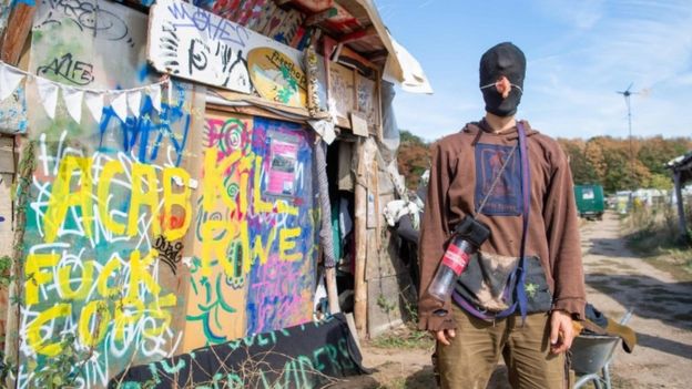 A hooded environmentalist stands at a camp the Tagebau Hambach mine in Kerpen, western Germany.