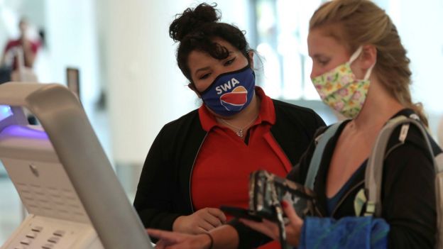 A Southwest Airlines Co. employee wears a protective mask while assisting a passenger at Los Angeles International Airport (LAX) on an unusually empty Memorial Day weekend during the outbreak of the coronavirus disease (COVID-19) in Los Angeles