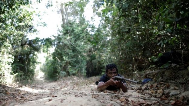 Paulo Paulino Guajajara holds a gun during the search for illegal loggers in September