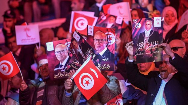 Supporters of President Essebsi wave photos of him and the country's founder at a meeting of the ruling party in Tunis, April 2019