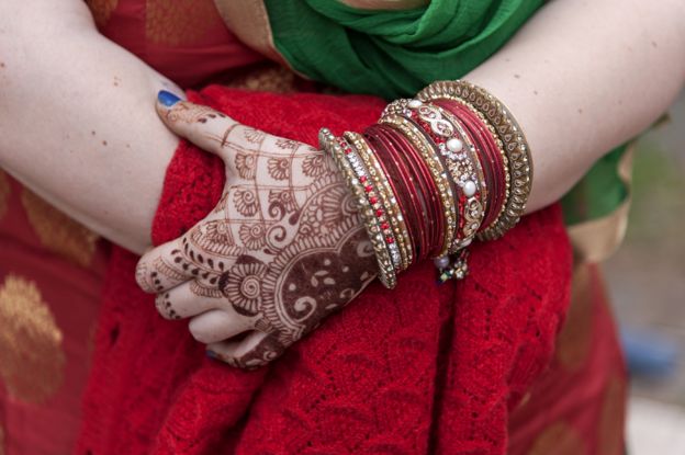 Mão de uma mulher sikh com jóias e tatuagem