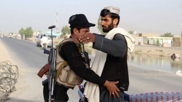 An Afghan security official frisks a ma in Kandahar (26 May 2017)