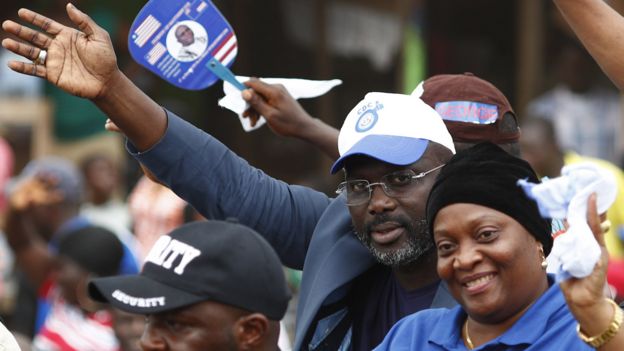 Liberian presidential candidate George Weah (C) from the Congress for Democratic Change (CDC) and running mate Jewel Howard Taylor (C-R), former wife of convicted former president Charles Taylor, wave to supporters during a campaign rally in Buchanan, Liberia, 30 September 2017.