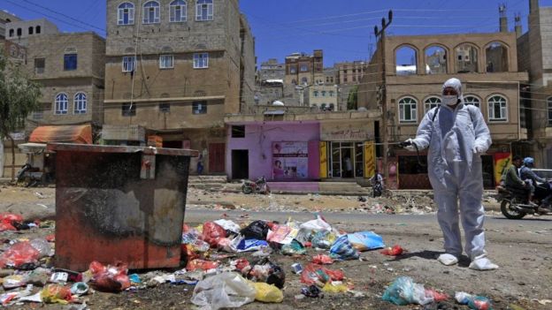 A Yemeni volunteer sprays disinfectant over garbage in the one of Sanaa's impoverished neighbourhoods, on March 30