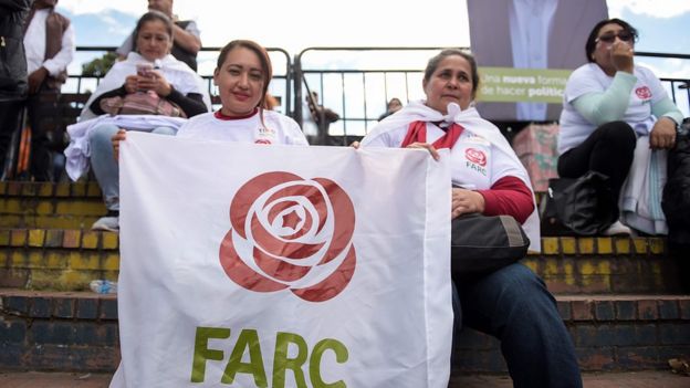 Dos mujeres sostienen una pancarta con el logo de la FARC.