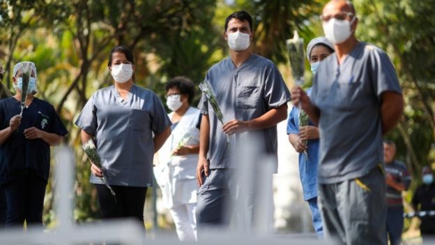 Médicos con rosas en la mano para homenajear a una enfermera que murió por coronavirus.