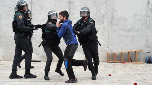 Tres policías detienen a un hombre durante el referéndum en Cataluña.