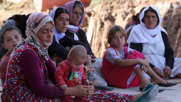 Mulheres e crianças yazidis sentadas no chão