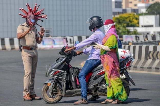 Police inspector Rajesh Babu (left) wearing a coronavirus-themed helmet speaks to motorists during a government-imposed nationwide lockdown as a preventive measure against the COVID-19 coronavirus in Chennai on 28 March 2020