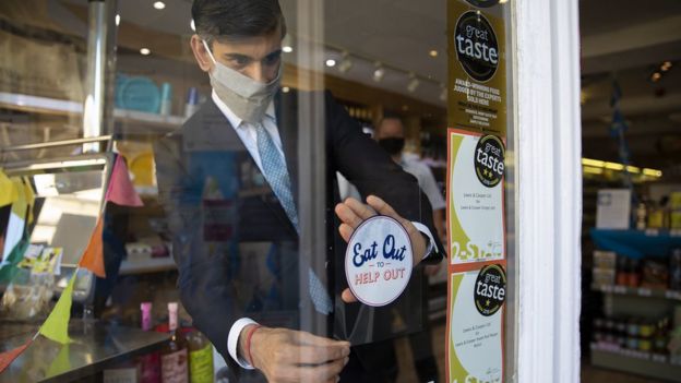 Chancellor Rishi Sunak places a sticker promoting the scheme on a window