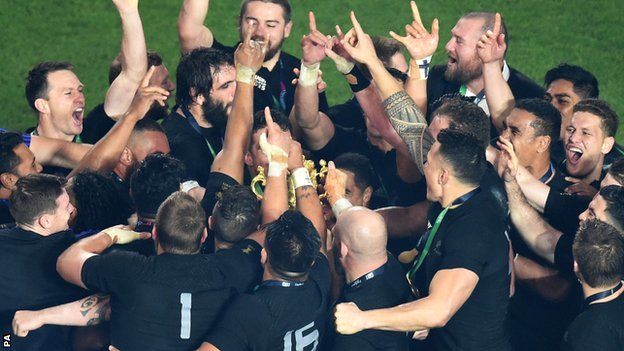 New Zealand huddle round the Webb Ellis Cup