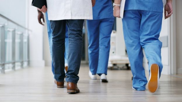 Profissionais de saúde caminham em corredor de hospital