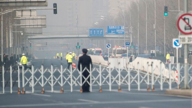Chinese policemen block a road as a procession believed to be North Korean officials pass near Diaoyutai State Guesthouse in Beijing