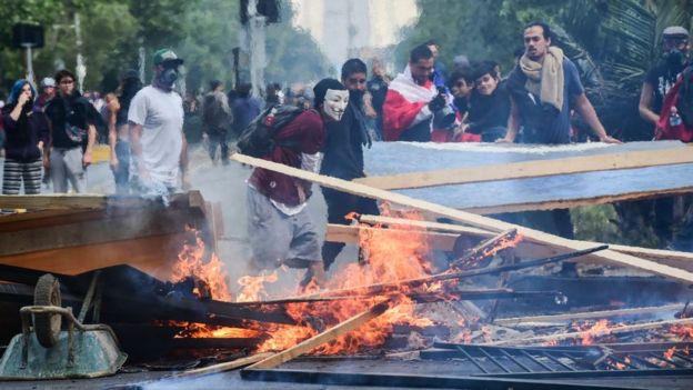 manifestantes ante maderas en llamas en Santiago de Chile