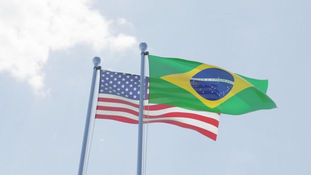 Bandeiras dos EUA e do Brasil sob o céu