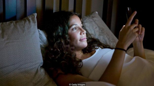Mulher usa smartphone antes de dormir