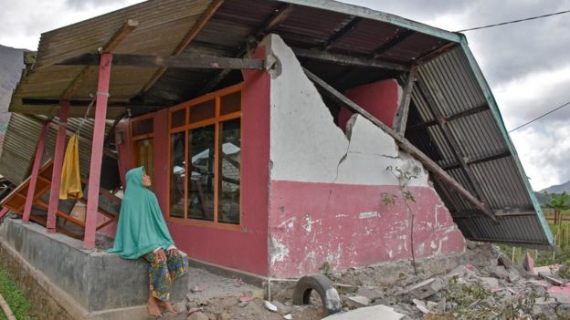 A villager sits at her damaged house after an earthquake hit Sembalun Bumbung village in Lombok Timur, Indonesia, July 29, 2018.