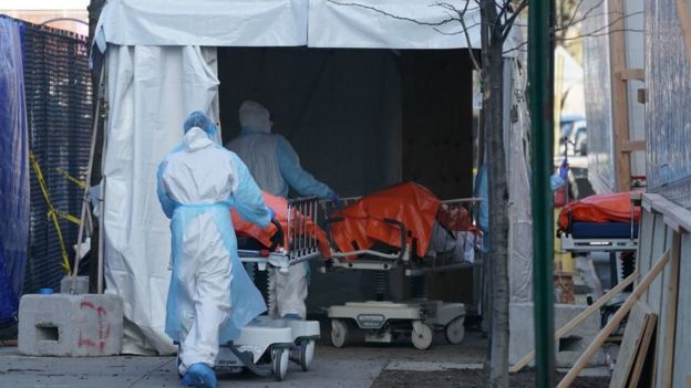 Bodies are loaded onto a refrigerated lorry which is serving as a makeshift morgue.