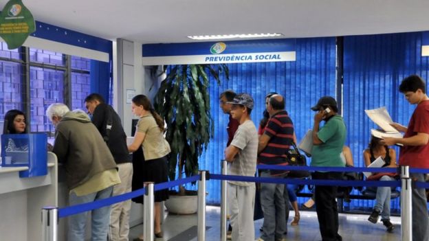 Pessoas em fila dentro de agência do INSS