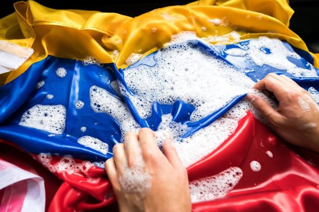 Manos lavando una bandera colombiana.