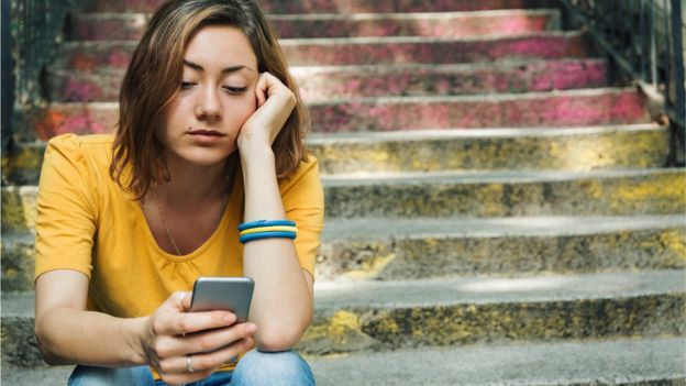 Bored young woman looking at smartphone