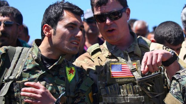 This file photo taken on April 25, 2017 shows a US officer, from the US-led coalition, speaking with a fighter from the Kurdish People