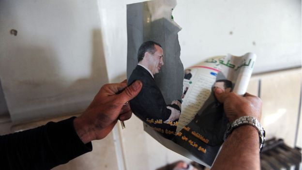 Suriye'de silahlı bir muhalif, Erdoğan ile Esad'ı el sıkışırken gösteren, çatışmalar sırasında yırtılmış bir dergi fotoğrafını tutuyor (10 Kasım 2012)