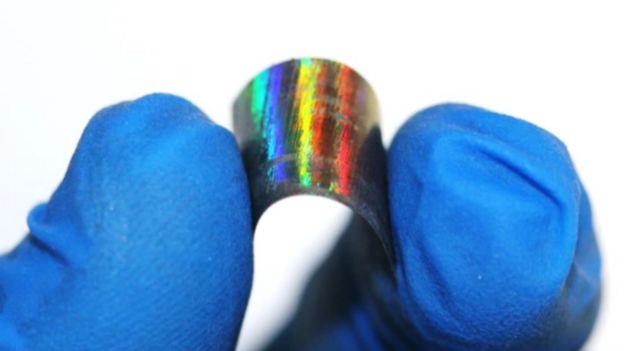Muestra de madera metálica doblada en la mano de un investigador