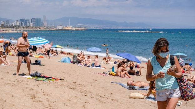 A woman wearing a face mask is seen leaving the beach. The city of Barcelona faces new outbreaks of coronavirus cases with new mobility restrictions and recommendations to avoid travelling outside the city.