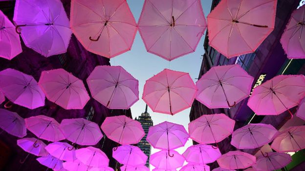 Calle adornada por completo con paraguas rosas