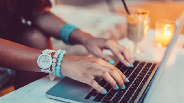 manos de mujer en teclado de computadora.