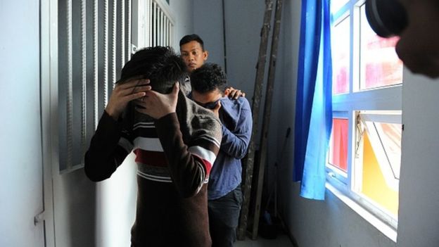 Two Indonesian men walk into a cell prior to their trials at a sharia court in Banda Aceh on May 17, 2017