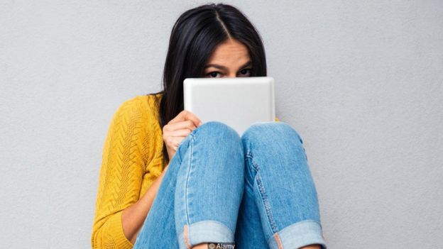 Una mujer escondida tras una tableta