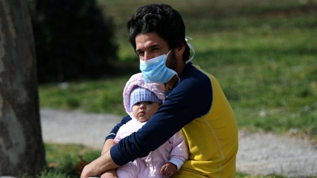 A man holds a baby outside the AHEPA hospital, where the first confirmed coronavirus case is being treated, in Thessaloniki, Greece,