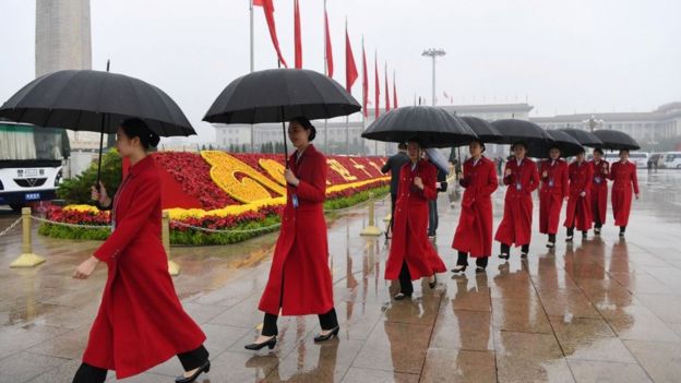 Asistentes al congreso con paraguas en la plaza Tianamén.