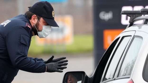 A policeman wearing a face mask warns a driver on the road between Codogno and Casalpusterlengo
