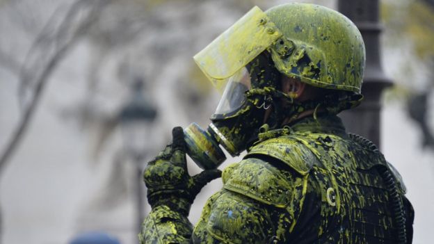 A Riot police officer covered with yellow paint pictured near Arc de Triomphe area
