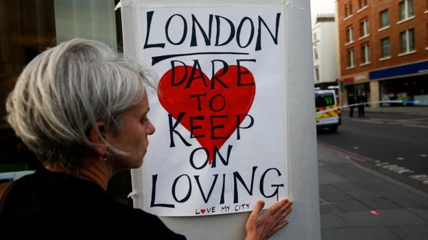A woman sticks a sign up saying:
