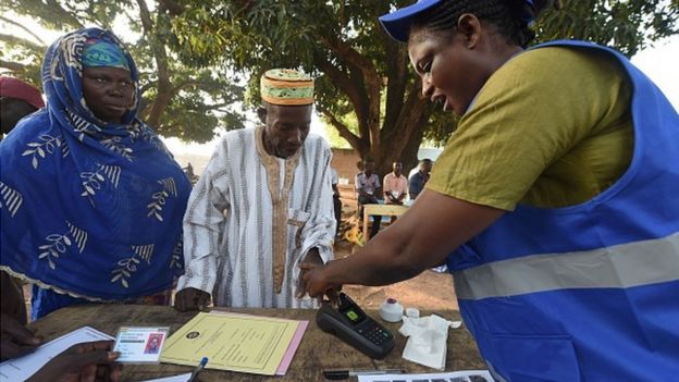 An official of the Electoral Commission (EC) helps a voter to do biometric verification before casting his vote for the presidential election at Bole district in northern Ghana, on December 7, 2016.