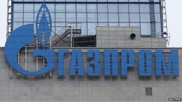 An employee stands near a window, with the company logo of Gazprom installed on a building, at the headquarters of the Russian natural gas producer in Moscow