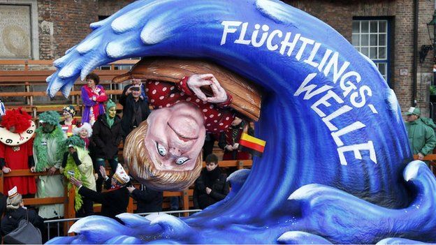 A carnival float with a papier-mache caricature shows German chancellor Angela Merkel on a boat being overturned by a wave labelled 'refugee wave'.