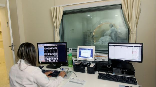 Profissional da saúde observa realização de tomografia