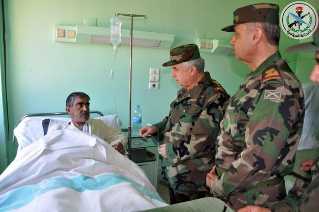 A handout photo made available by Syrian Arab news agency Sana shows Syrian Chief of the General Staff of the Army and Armed Forces Gen. Ali Abdullah Ayoub (C), visiting a Syrian pilot wounded in the US attack at Shayrat, 7 April