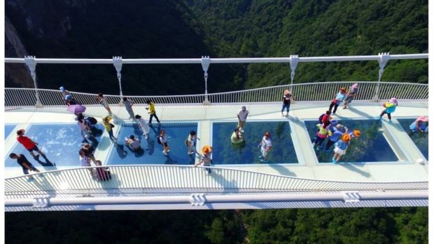 Visitors walk across a glass-floor suspension bridge in Zhangjiajie in southern China's Hunan Province Saturday, Aug. 20, 2016