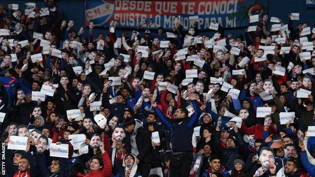 Nacional fans holding Luis Suarez masks and 'Suarez to Nacional' banners