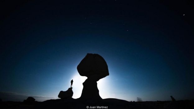 رجل يقف على صخرة في الصحراء ليلا